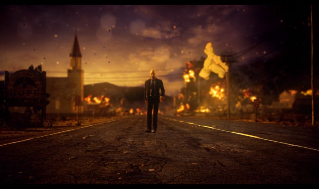 Screenshot of Agent 47 walking away like a badass, as the town in the background burns.